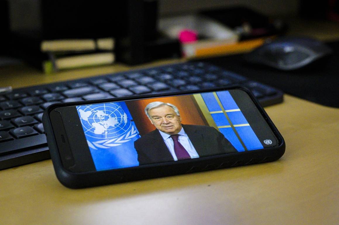 På en mobiltelefon vises Generalsekretær António Guterres som holder en digital pressebriefing om den pågående koronapandemien. Foto: UN photo/Manuel Elias